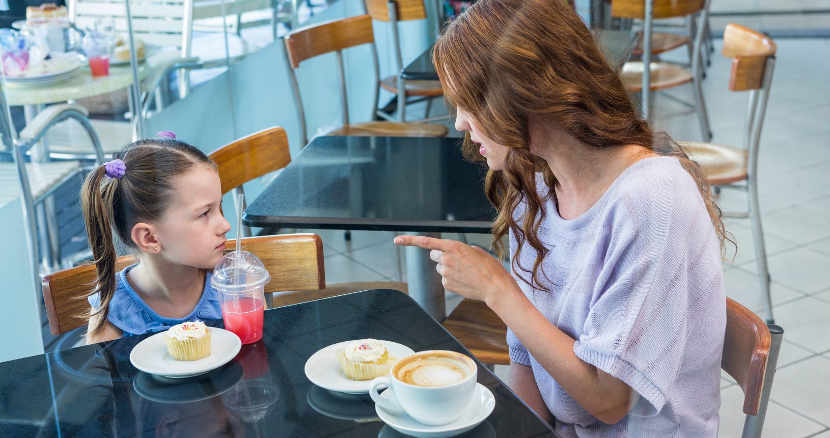 Mother and daughter arguing at table in coffee shop
