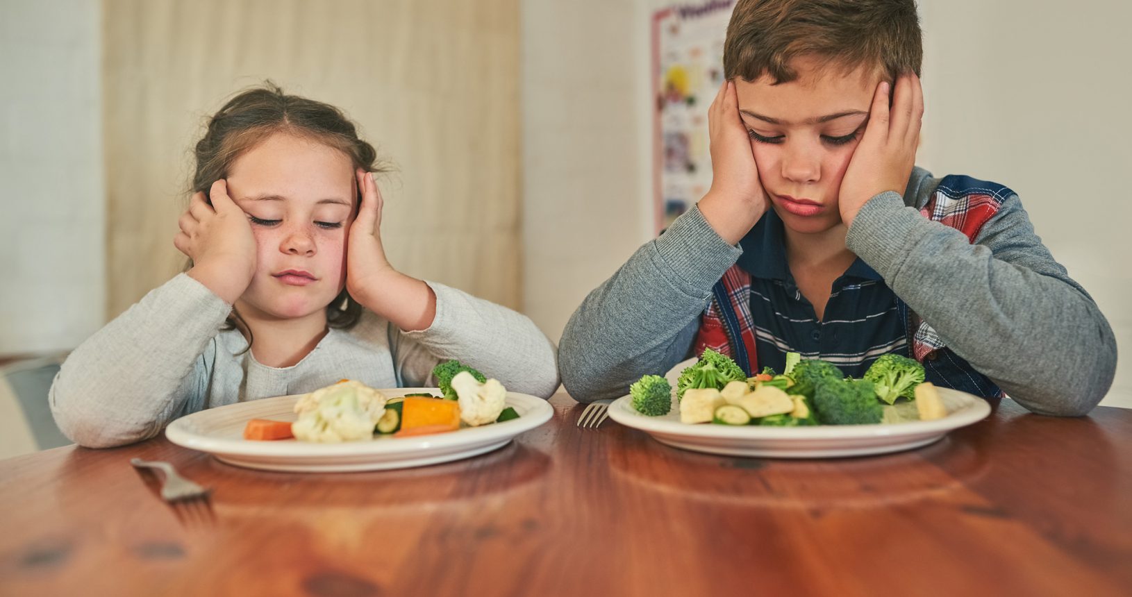 Wed rather go on a hunger strike. Cropped shot of two grumpy children refusing to eat their vegetables.